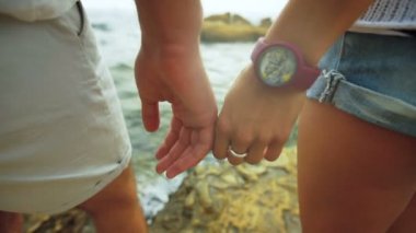 Bir erkek ve bir kadın şefkatle, taşa kalırken elele yakın çekim.