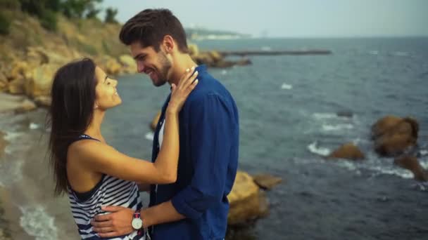 Casal feliz abraçando uns aos outros, enquanto em pé em uma bela praia de pedra . — Vídeo de Stock