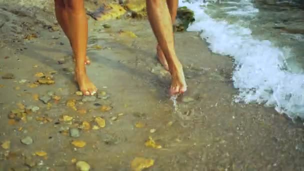 Barefoot young couple walking on the beautiful stony beach. — Stock Video