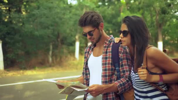 Happy glimlachend jonge vriend en zijn aantrekkelijke vriendin lopen samen met een kaart op de handen. — Stockvideo