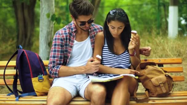 Dois jovens comendo sorvete, sentados no banco de um belo parque . — Vídeo de Stock