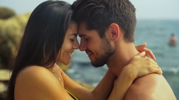 Gelukkige lachende paar in zwemmen pak knuffelen op het mooie strand. — Stockvideo