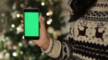 Yakın çekim kadın smartphone dokunmadan eller. Chroma anahtar yeşil ekran. Yakın çekim. Hareket izleme. ile Noel dekorasyon arka plan bulanıklık