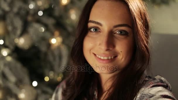 Ünnepek, a tél és az emberek koncepció - santa kalap selfie átveszi a karácsonyfa otthon-boldog fiatal nő — Stock videók