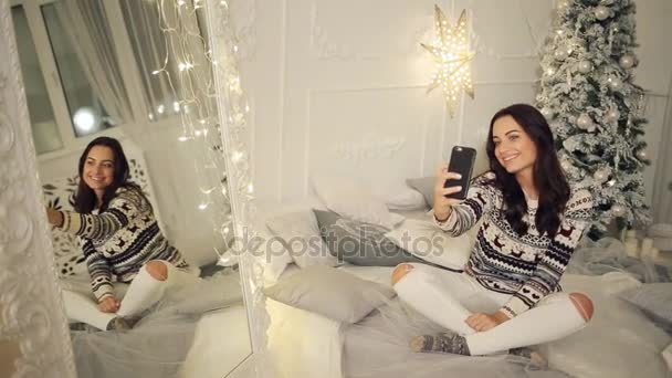 Semester-, vinter- och människor koncept - glad ung kvinna tar selfie över julgran hemma — Stockvideo