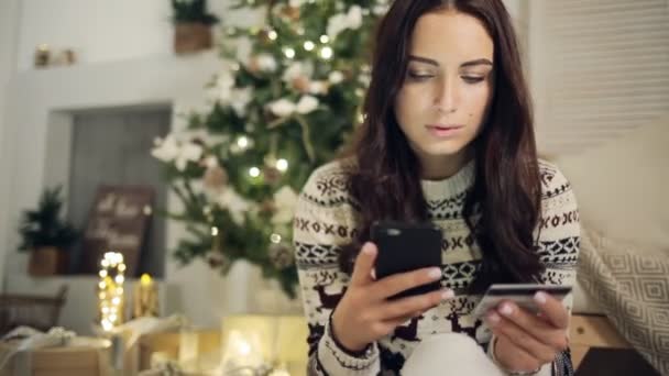 Молода жінка купує подарунки з кредитною карткою на Різдво вдома — стокове відео