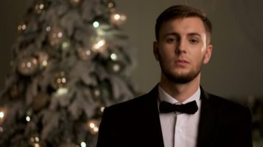 Kameraya poz Chistmas zamanında şık takım elbise giymiş yakışıklı genç adam.