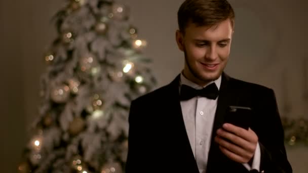 Junger gutaussehender Mann im schicken Anzug, der am Neujahrstag mit dem Handy plaudert. — Stockvideo