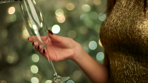 Kvinna i guld klänning håller ett glas champagne sparkle på nyårsafton. — Stockvideo