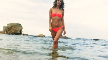 Sahilde poz, kırmızı mayo giyen güzel genç model.