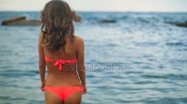 Seksi genç modeli ıssız Sahilde yürüyüş bir kırmızı mayo.