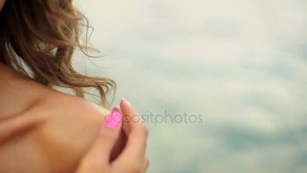 Сексуальна молода жінка торкається її красиве плече і її кучеряве волосся на пляжі . — стокове відео