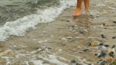 Su bir çöl Beach üzerinde yürüyen genç bir kadın güzel bir vücut yakın çekim.