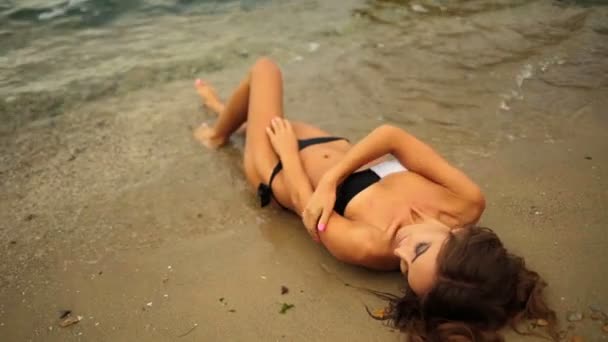 Giovane donna sexy glamour sdraiato sulla spiaggia e toccando il suo bel corpo in forma . — Video Stock