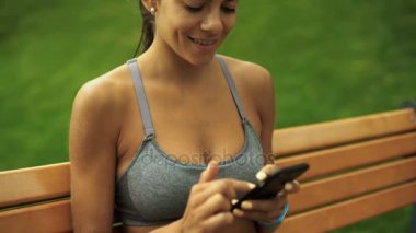 Güzel bir yeşil yerde otururken ona smartphone kullanan kadın genç seksi tabaklanmış.