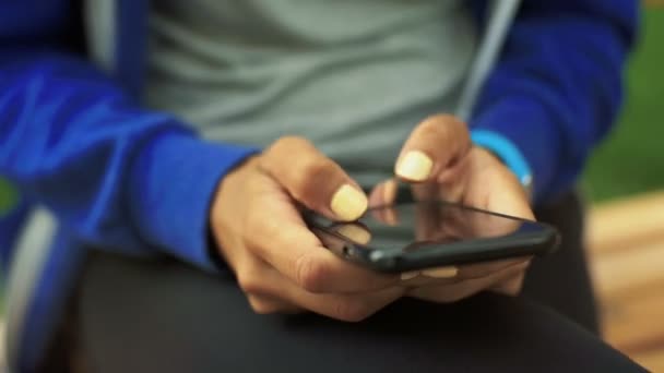 Jovem sentada em um banco e conversando com seus amigos via celular . — Vídeo de Stock