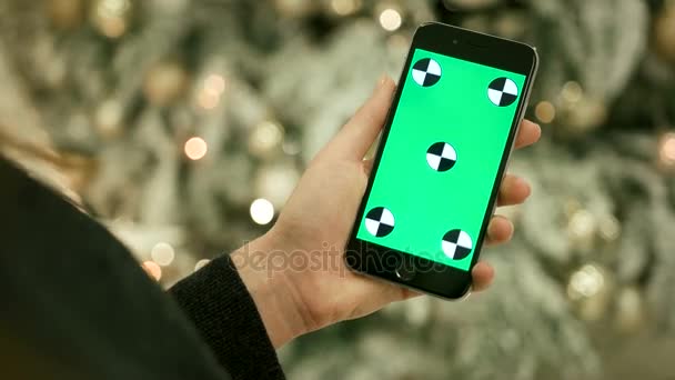 Gros plan des mains féminines touchant l'écran vert sur le téléphone mobile. Chroma Key. Ferme là. Suivi du mouvement. Vertical.with flou fond de décoration de Noël — Video