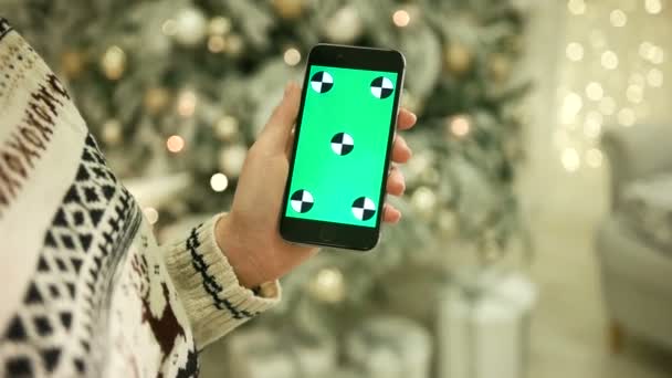 Gros plan des mains féminines touchant l'écran vert sur le téléphone mobile. Chroma Key. Ferme là. Suivi du mouvement. Vertical.with flou fond de décoration de Noël — Video