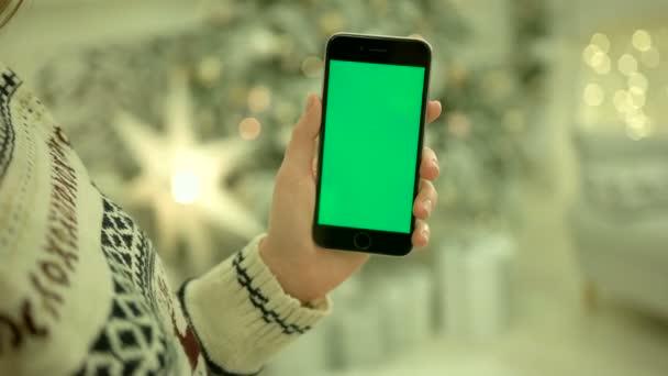 Primer plano de las manos femeninas tocando la pantalla verde en el teléfono móvil. Chroma Key. De cerca. Movimiento de rastreo. Vertical.with difuminación Navidad decoración fondo — Vídeo de stock