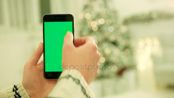 Primo piano delle mani femminili che toccano lo schermo verde sul telefono cellulare. Chiave cromatica. Chiudete. Movimento di localizzazione. Vertical.with sfocatura natale decorazione sfondo — Video Stock