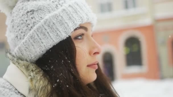 Ελκυστική όμορφη κοπέλα ποζάρει και φλερτ για την κάμερα πέρα από χιονισμένο πόλη υπόβαθρο — Αρχείο Βίντεο