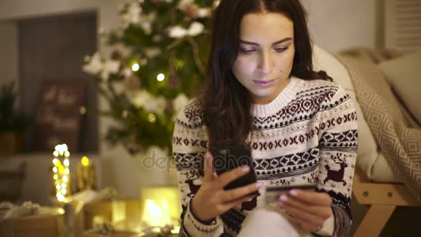 Belle jeune femme assise sur un sol tenant téléphone portable et carte de crédit sur les mains . — Video