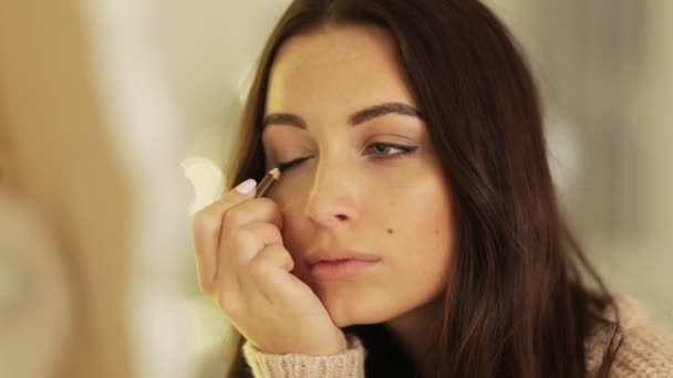 Primo piano di attraente giovane signora seria con i capelli castani facendo make-up naturale a casa . — Video Stock