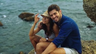 Sahilde poz ve kameraya gülümseyen iki genç mutlu insanlar.