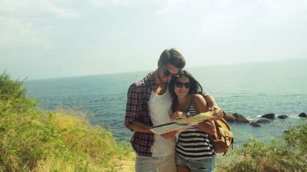 Zwei lächelnde Menschen, die am Strand bleiben, einen schönen sonnigen Tag genießen und neue Reiseziele planen. — Stockvideo