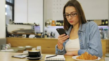 Kafede otururken SMS gönderme istimal hareket eden telefon, manifatura Masaj, genç güzel kadın