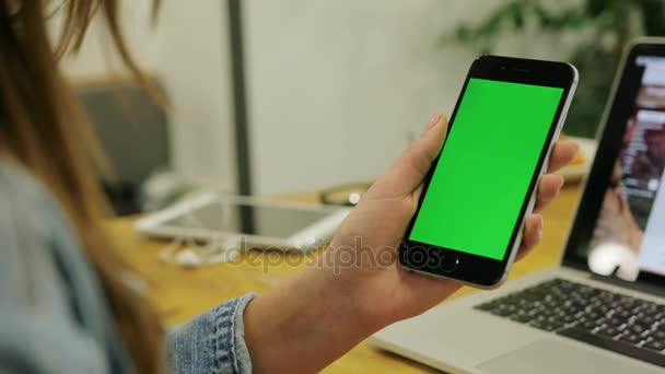 Mujer viendo vídeo en smartphone con pantalla verde. Vídeo de cerca de las manos de las mujeres sosteniendo el teléfono móvil. Clave de croma. De cerca. Vertical — Vídeo de stock