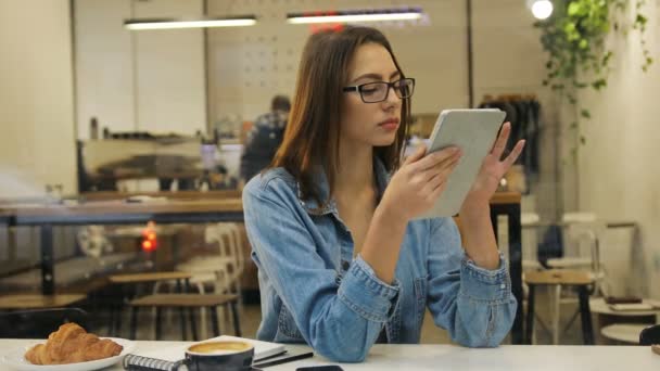 Vacker ung kvinna med hjälp av tablet PC i café utsikten genom fönstret — Stockvideo