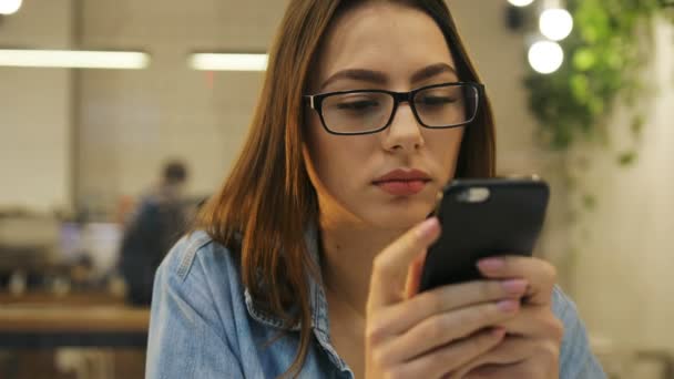 Jovem mulher bonita usando telefone celular, mensagens de texto massagista, enviando sms enquanto sentado no café — Vídeo de Stock