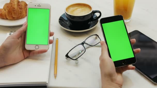 两个女人用绿屏的智能手机。特写的两个女人手里拿着移动电话的视频。色度键。垂直 — 图库视频影像