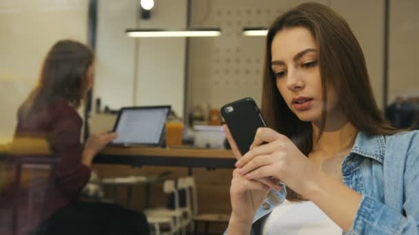 Krásná mladá žena pomocí smartphone v kavárně, pohled z okna. Žena používající mobilní telefon v kavárně. Rozmazané pozadí — Stock video