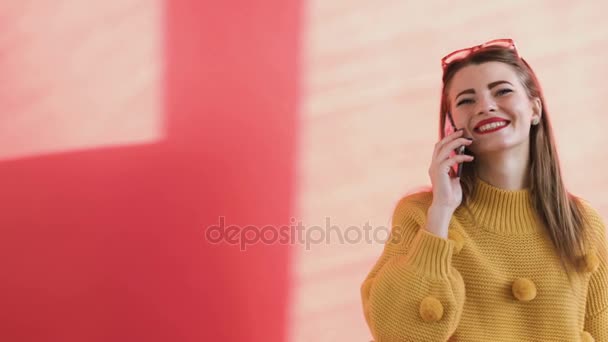 Девушка разговаривает по телефону возле дома — стоковое видео