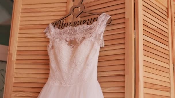 Schöne luxuriöse Hochzeitskleid auf Kleiderbügel auf Holz Hintergrund. Hochzeitsvorbereitung — Stockvideo