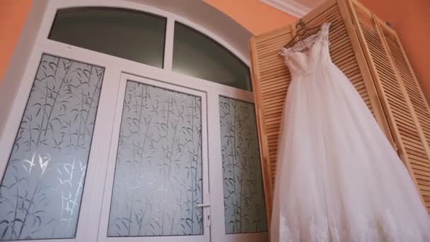 Hermoso vestido de novia largo elegante en percha sobre fondo de madera. Preparación de boda — Vídeos de Stock