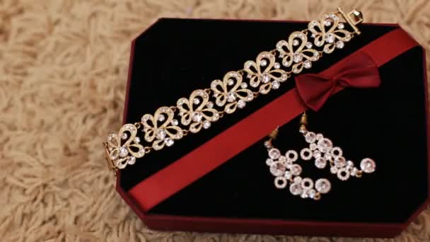 Close up view of golden bracelet and earrings with diamonds in jewelry box. Beautiful luxurious jewelery in gift box with black cloth. — Stock Video