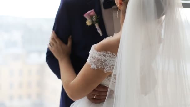 Bräutigam und Braut mit Blumenstrauß schauen sich an und küssen sich vor dem Fenster im Haus. wunderschönes Hochzeitskleid. gerade verheiratet. Zeitlupenaufnahme — Stockvideo