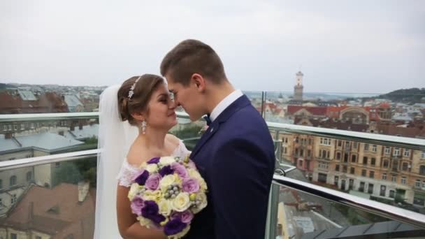 Жених и невеста целуются перед старым городским пейзажем на крыше. Львов, Украина. Вид на город — стоковое видео