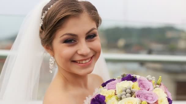 Bella sposa profumato bouquet di fiori di nozze e guardando la fotocamera in sfocato sfondo della città vecchia. Da vicino. — Video Stock