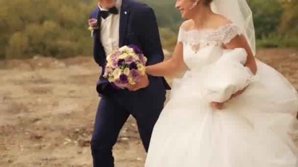 Sposo e sposa in esecuzione nel parco il giorno d'estate. Matrimonio. Colpo esterno — Video Stock