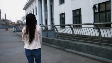 Kot pantolon ve beyaz ceket giyiyor şehir sokakta yürüyen uzun siyah saçlı güzel kadın