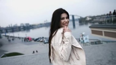 Güzel gülümseyen esmer Bayan ceketi Köprüsü, Nehri üzerinde arka plan üzerinde yürüyen kapalı alarak