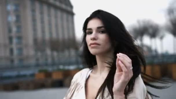 Dult αισθησιακή γυναίκα αγγίζει τα μαλλιά της μακρύ σκούρο χρώμα, φορώντας ρούχα την άνοιξη, σε εξωτερικούς χώρους — Αρχείο Βίντεο