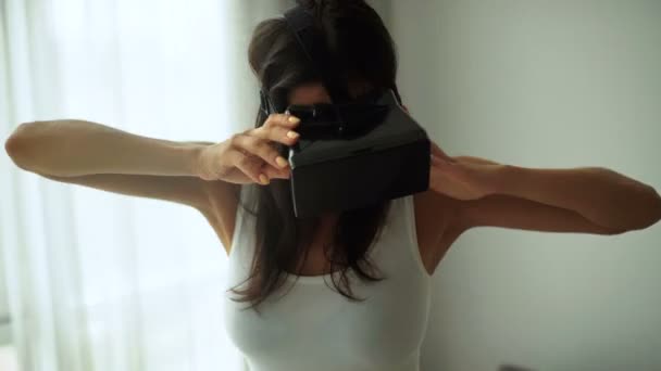 Yatak odasında, sanal gerçeklik gözlükleri tadını beyaz t-shirt giyen güzel tabaklanmış kadın. — Stok video