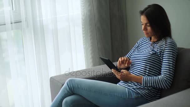Молодая красивая женщина держит планшет в руках и расслабляется дома . — стоковое видео