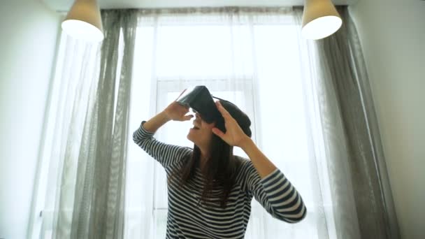 Fiatal barna nő a farmer és a kényszerzubbony, élvezve a virtuális valóság szemüveg otthon közelről. — Stock videók