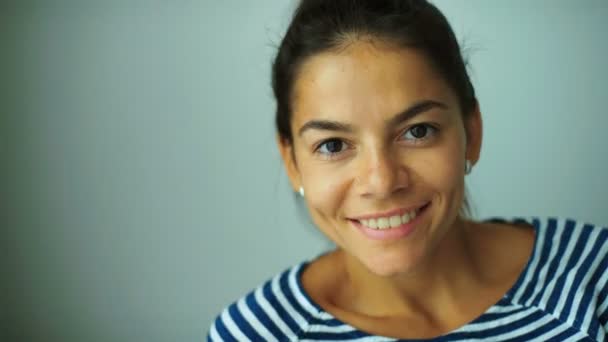 Jolie jeune femme souriante avec peu de maquillage posant sur la caméra à la maison . — Video